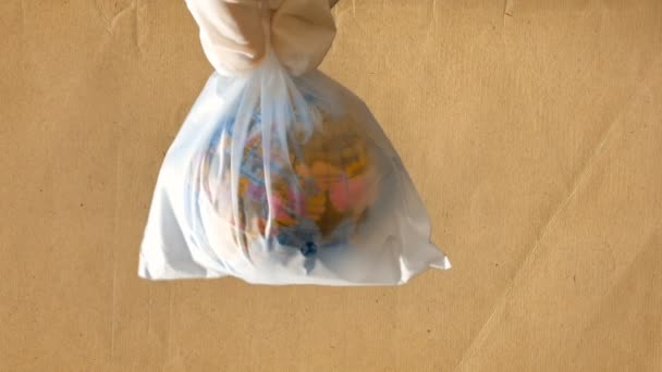 En tonårig flicka innehar en plastpåse i handen som innehåller en mini globe, returpapper bakgrund, material lämplig för att berätta om problemen med ekologi och respekt för naturen och världen — Stockvideo