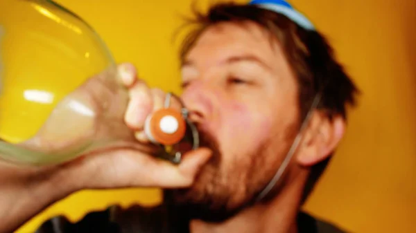 Unhappy and depressed man celebrates the carnival or new year, with party horn on a yellow background, footage ideal for representing bad holidays and comic situations — Stock Photo, Image