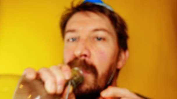 Unhappy and depressed man celebrates the carnival or new year, with party horn on a yellow background, footage ideal for representing bad holidays and comic situations — Stock Video