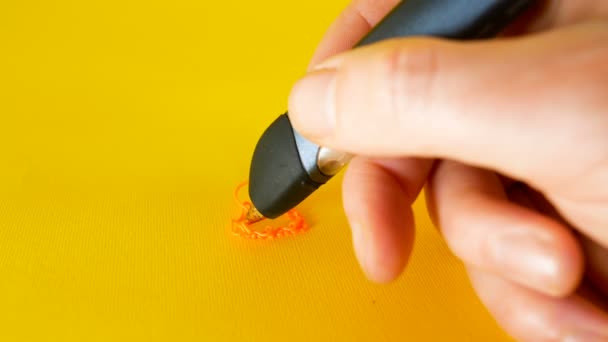 Une main mans dessine avec un stylo imprimante 3D sur un fond jaune, des images idéales pour des sujets tels que l'innovation, la technologie — Video