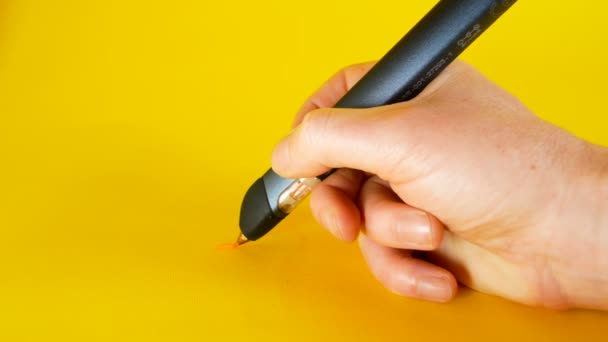 A mans hand draws with a 3d printer pen on a yellow background, footage ideal for topics such as innovation, technology — Stock Video