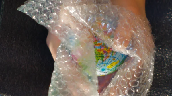Gençler yardım küçük bir küre tutan, bir levha bubble wrap, ekoloji Temalar temsil etmek için ideal görüntüleri görüntüleniyor