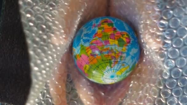 Una mano de adolescentes sostiene un pequeño globo, encima aparece una hoja de plástico de burbujas, material de archivo ideal para representar temas de ecología — Vídeos de Stock