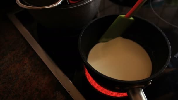 Young pastry warms milk in a saucepan, footage ideal for representing homemade pastry — Stock Video