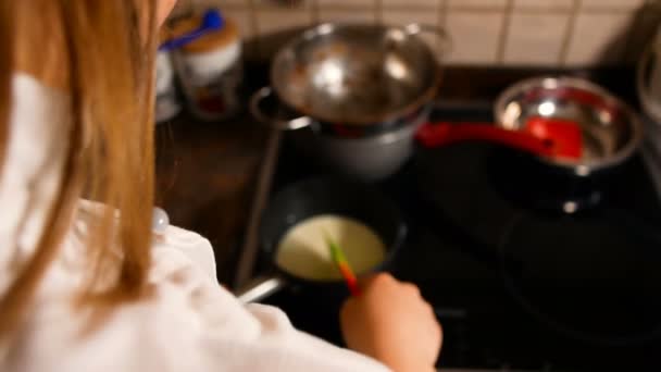 Giovane pasticceria riscalda il latte in una casseruola, filmato ideale per rappresentare la pasticceria fatta in casa — Video Stock