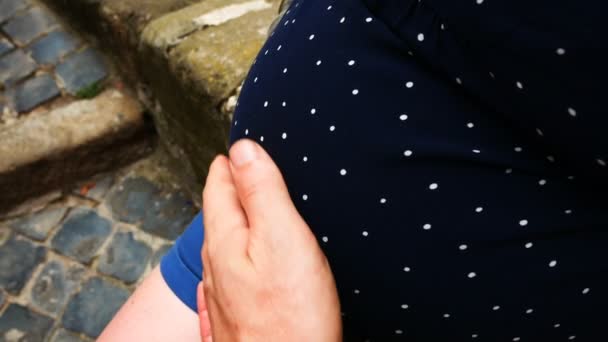 Terhes nő ül, öltözött egy pöttyös kismama ruha simogató hasát a kezével — Stock videók