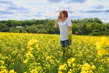 Polene ve çiçek mevsimine alerjisi olan bir kız, çiçek tarlasında hapşırır.