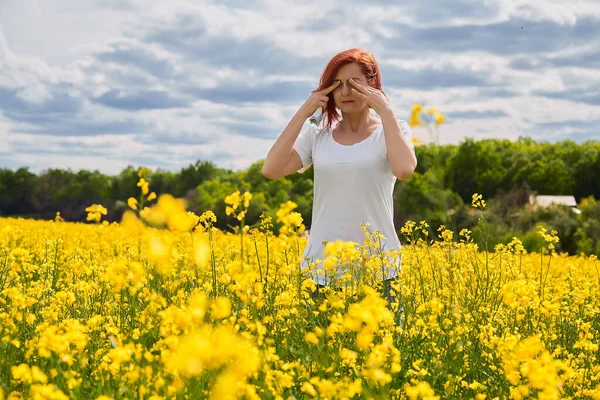 Girl cries and rubs her eyes due to allergy to pollen