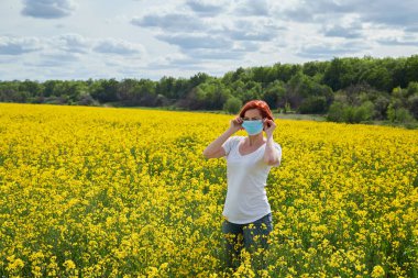 Çiçek açan kolza tohumu tarlasında tıbbi maskeli polen alerjisi olan kız.