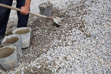 Construction work, worker fill gravel with a shovel in buckets