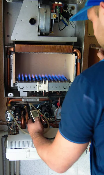 A technician serving a gas boiler for hot water and heating. Adjustment of the gas pressure gauge by pressure adjustment