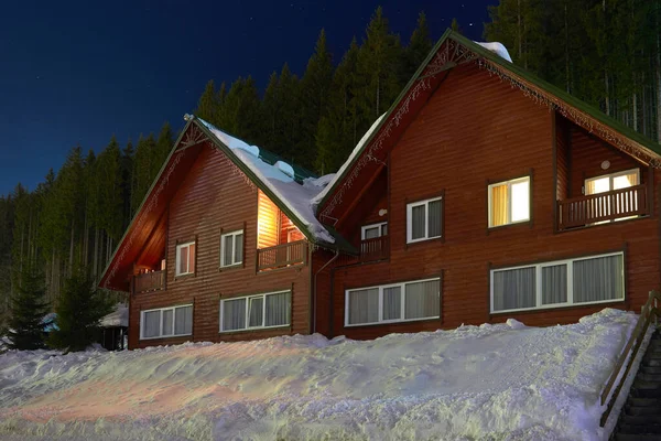 two wooden fairytale house in the snow a winter evening. A house for holidays and vacations in the forest,