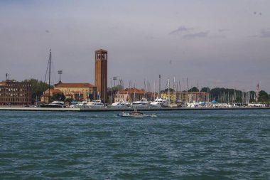 İtalya. Parlak bir yaz gününde Venedik lagünü. Deniz tekneleri, renkli evler ve eski kule ile Venedik manzara.