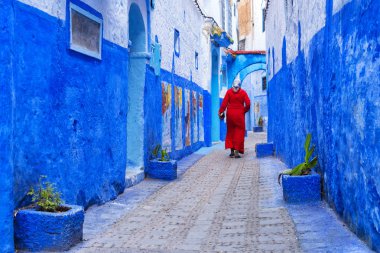 Tanınmayan Fas kadın mavi yapılarıyla için bilinen kuzeybatı Fas Chefchaouen Medina, Fas, küçük kasabasında bir sokakta yürüyen kırmızı geleneksel giysileri (jellaba)