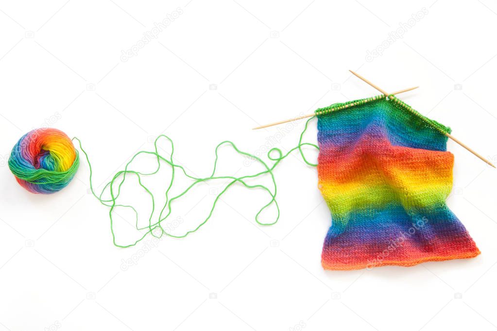 Bright rainbow knitted fabric. Knitting needles. White background.