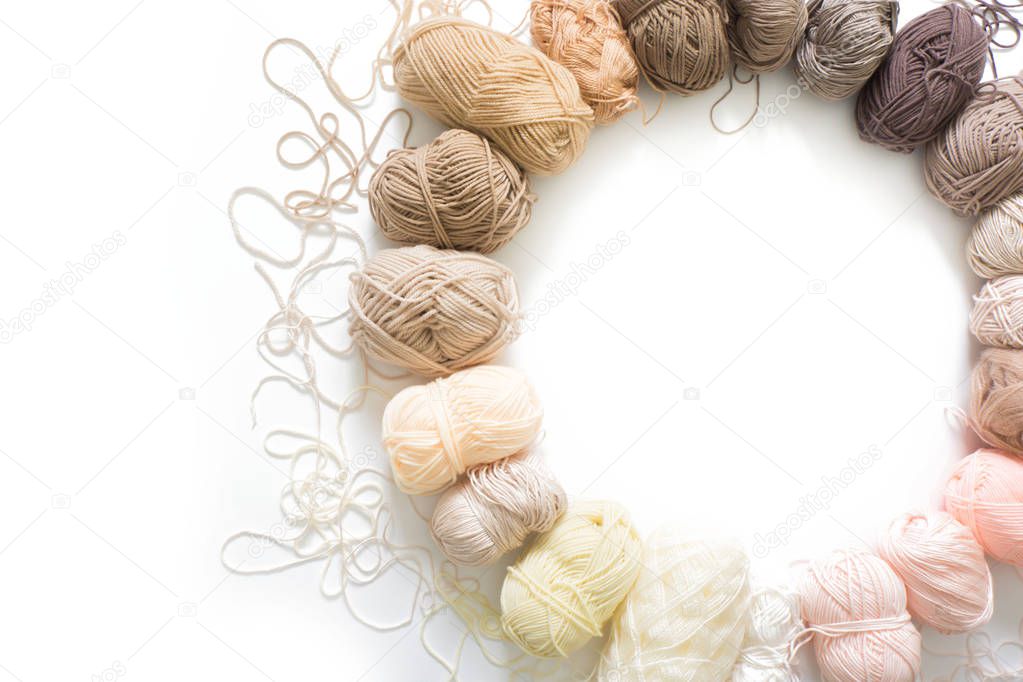 The yarn is beige, brown, gray and white. Knitting needles, scissors, knitting, knitted fabric.