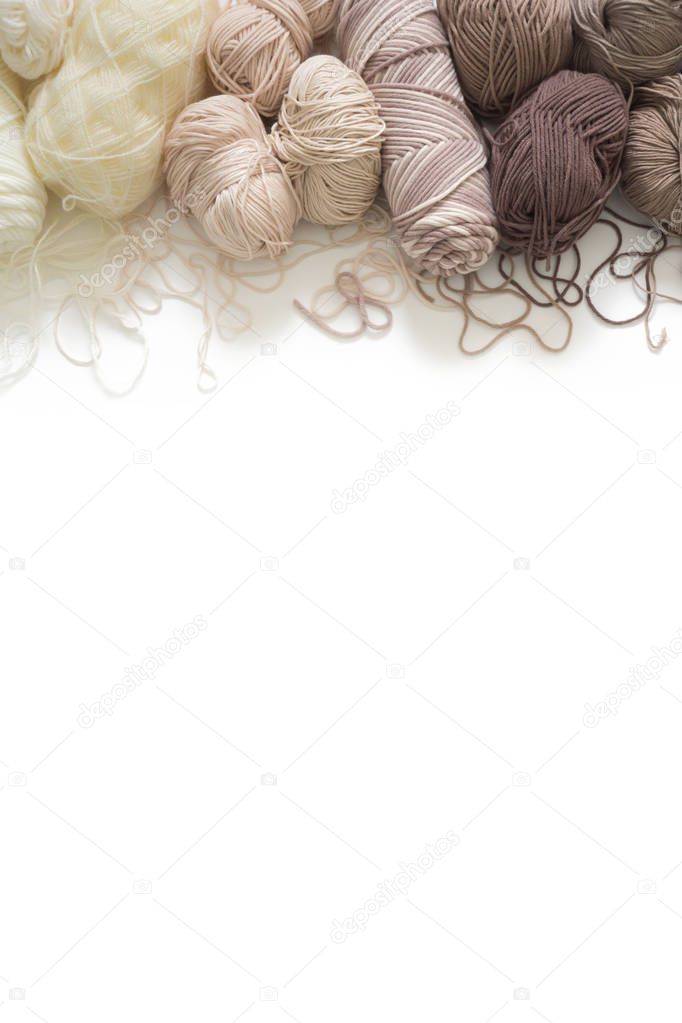 The yarn is beige, brown, gray and white. Knitting needles, scissors, knitting, knitted fabric.