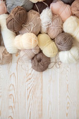 İplik olduğunu bej, kahverengi, gri ve beyaz. Arka plan yaşlı ahşap. İğneler, makas, kahve, örgü, örgü örme kumaş.