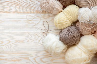 İplik olduğunu bej, kahverengi, gri ve beyaz. Arka plan yaşlı ahşap. İğneler, makas, kahve, örgü, örgü örme kumaş.