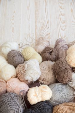 İplik olduğunu bej, kahverengi, gri ve beyaz. Arka plan yaşlı ahşap. İğneler, makas, kahve, örgü, örgü örme kumaş.