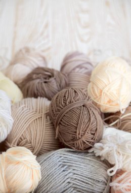 İplik olduğunu bej, kahverengi, gri ve beyaz. Arka plan yaşlı ahşap. İğneler, makas, kahve, örgü, örgü örme kumaş.