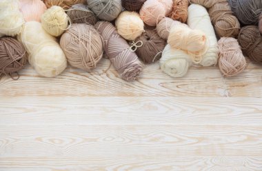 İplik olduğunu bej, kahverengi, gri ve beyaz. Arka plan yaşlı ahşap. İğneler, makas, kahve, örgü, örgü örme kumaş.