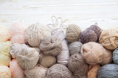 İplik olduğunu bej, kahverengi, gri ve beyaz. Arka plan yaşlı ahşap. İğneler, makas, kahve, örgü, örgü örme kumaş.