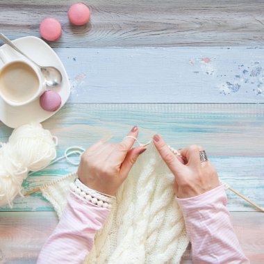 Örgü örgü iğne ile. Beyaz kumaş örme. Kahve Americano. Arka plan ışığı yaşlı.