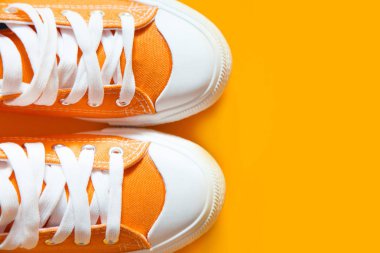 Turuncu bir arka plan üzerinde kısa düşük parlak spor ayakkabı.