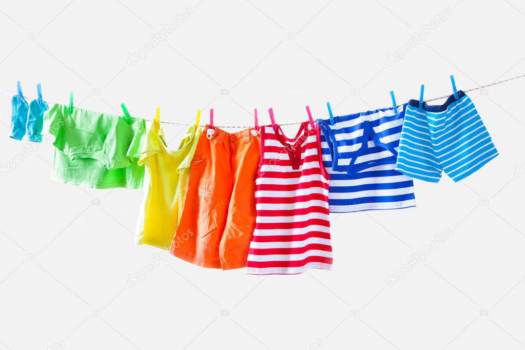 Clothesline with hanging baby clothes on yellow background
