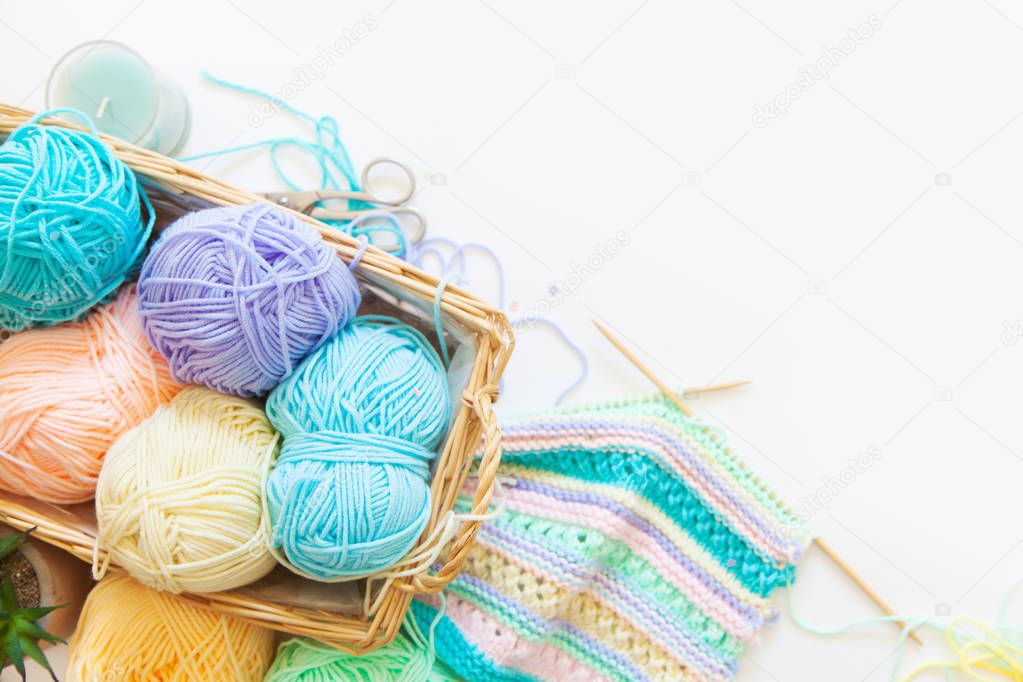 top view of colored yarn balls and knitting needles isolated on white