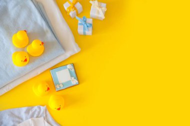 Bebek giyim, banyo malzemeleri, oyuncaklar ve sağlık bakım aksesuarları ile sarı arka plan üzerinde. Liste veya genel bilgileri hamilelik ve bebek duş alışveriş diliyorum. Yukarıdan görüntüleyin. Çocuk besleme değiştirme ve banyo