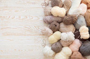 İplik olduğunu bej, kahverengi, gri ve beyaz. Arka plan yaşlı ahşap. İğneler, makas, kahve, örgü, örgü örme kumaş.