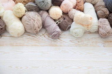 İplik olduğunu bej, kahverengi, gri ve beyaz. Arka plan yaşlı ahşap. İğneler, makas, kahve, örgü, örgü örme kumaş.