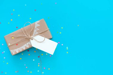 Zanaat broun hediye kutusu. Renkli bir çelenk, bayrakları çizim. Arka plan mavi ve turkuaz. Konfeti.