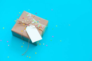 Zanaat broun hediye kutusu. Renkli bir çelenk, bayrakları çizim. Arka plan mavi ve turkuaz. Konfeti.