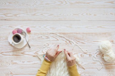 Örgü örgü iğne ile. Beyaz kumaş örme. Kahve Americano. Arka plan ışığı yaşlı.