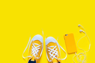 Sarı bir arka plan üzerinde kısa düşük parlak ayakkabılar. Hareket eden telefon 