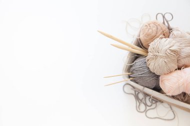 Bir sepet bej ve nötr iplik, doğal tonlar, örgü ve örgü. Konuşmalar, sulu, makas. Beyaz arkaplan.