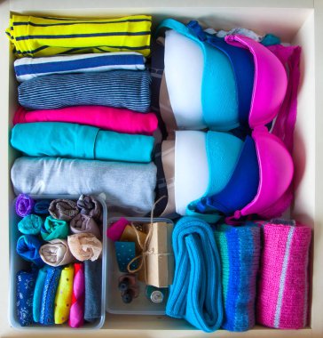 Neatly folded clothes with accessories in chest of drawers clipart