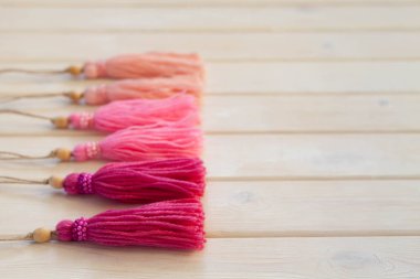 Pembe püsküllü. Arka plan beyaz ahşap.