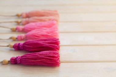 Pembe püsküllü. Arka plan beyaz ahşap.