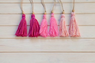 Pembe püsküllü. Arka plan beyaz ahşap.