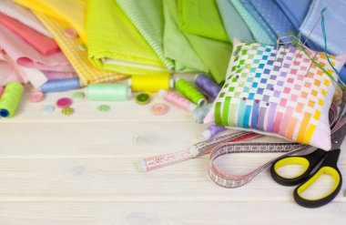 Dikiş aksesuarları beyaz bir arka plan üzerinde yalan. Ölçüm bandı, iplik, kumaş, İğne mili ve iğneler dikiş için.