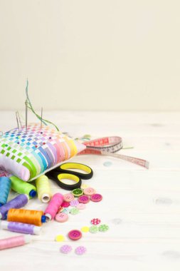 Dikiş aksesuarları beyaz bir arka plan üzerinde yalan. Ölçüm bandı, iplik, kumaş, İğne mili ve iğneler dikiş için.