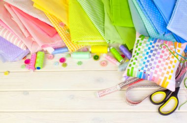 Dikiş aksesuarları beyaz bir arka plan üzerinde yalan. Ölçüm bandı, iplik, kumaş, İğne mili ve iğneler dikiş için.