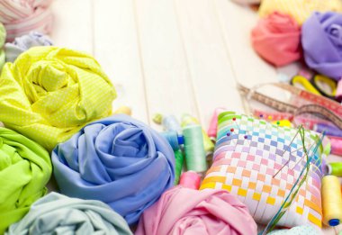 Dikiş aksesuarları beyaz bir arka plan üzerinde yalan. Ölçüm bandı, iplik, kumaş, İğne mili ve iğneler dikiş için.