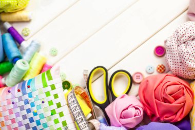 Dikiş aksesuarları beyaz bir arka plan üzerinde yalan. Ölçüm bandı, iplik, kumaş, İğne mili ve iğneler dikiş için.
