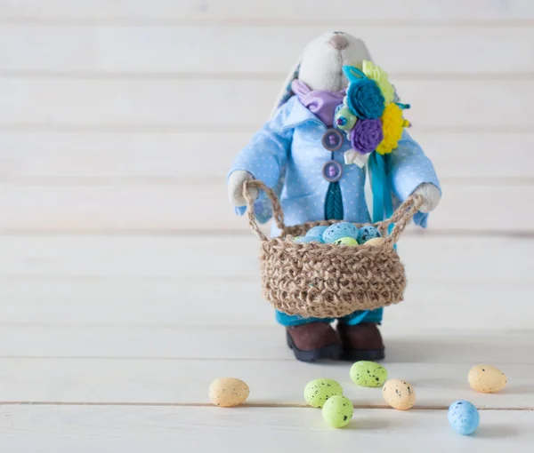 Handmade toys. Easter rabbit. Multicolored eggs. White background. Nest with eggs.