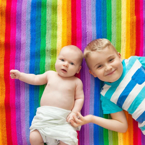 男孩们躺着 面带微笑 手牵手 彩虹毯 年龄较大和更年轻的兄弟 — 图库照片